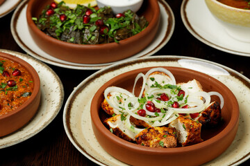 Georgian dish chicken with onion and pomegranate фтв dolma on wooden background