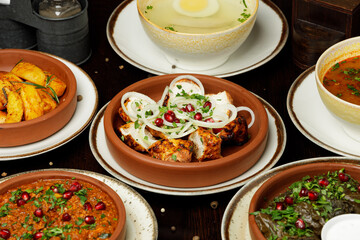 Georgian dish chicken with onion and pomegranate, Kuchmachi dish of chicken livers, chicken broth with egg, kharcho and fried potatoes on wooden background