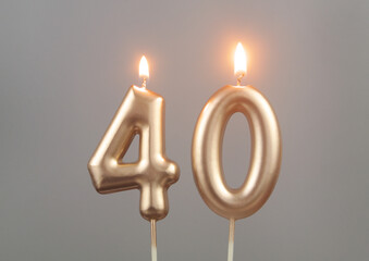 Burning gold birthday candles on gray background, number 40