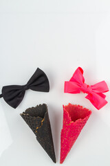 Black and pink waffle cones with bow ties. Mens and womens concept. Vertical shot white background.