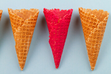 Close up red waffle ice cream cones and ordinary ones. Blue pastel background.