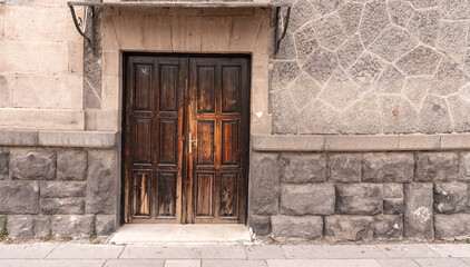 Fototapeta na wymiar Old classical stone house with rustic, brown, carved, vintage wooden door. Door textures and backgound.