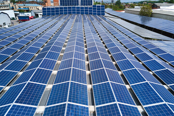 Aerial view of blue photovoltaic solar panels mounted on industrial building roof for producing...
