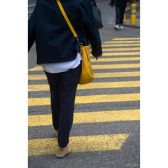 Closeup of legs of woman crossing the street on yellow zebra