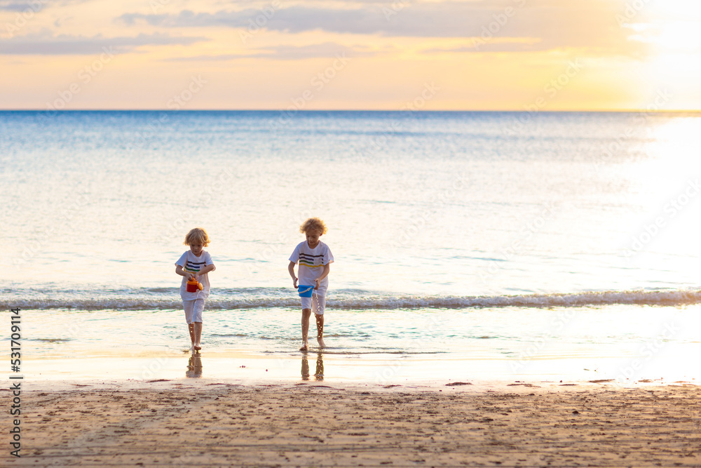 Wall mural Kids play on tropical beach. Sand and water toy.