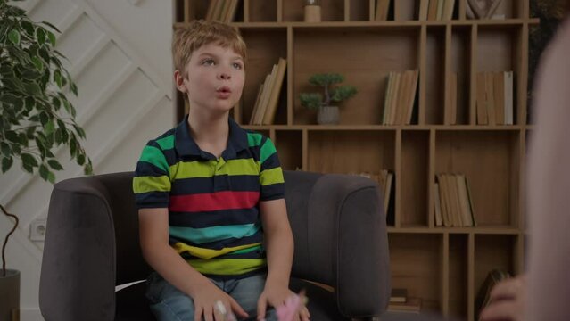 School boy working with speech therapist sitting on armchair. Children speech-language pathologists at work.