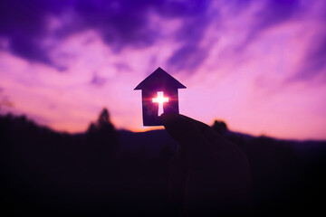Hand holding home cross shapes, with light of sunset purple color background,  christian silhouette...