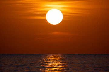 Fototapeta premium Ocean sunset. Big white sun on dramatic bright sky background, soft evening horizont over sea dark water