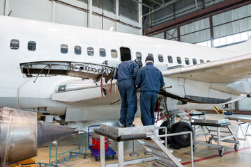 White passenger airplane in the hangar. Aircraft under maintenance. Preparation for engine mounting