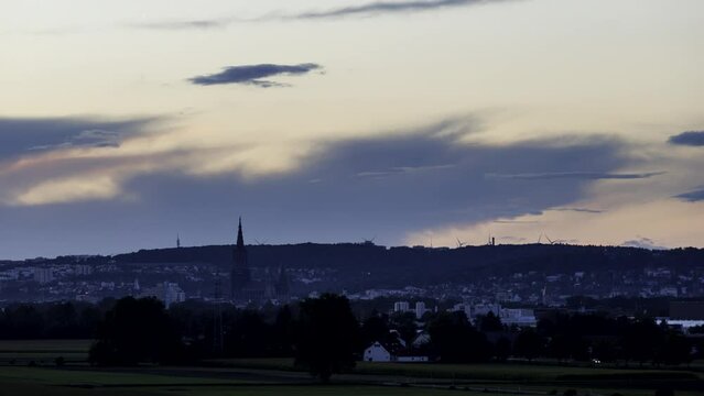 Time lapse shot at dusk with clouds of the cities of Neu-Ulm and Ulm with Ulm minster. In the background are the mountains Eselsberg and Michelsberg. Lights turn on while it gets darker.