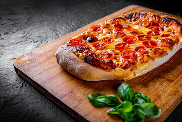 flatbread Pizza with Mozzarella cheese, Tomatoes, pepper, Spices and Fresh Basil. Italian pizza. Pizza Margherita or Margarita on Dark grey black slate background