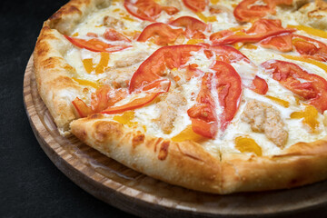 Pizza with vegetables, chicken and cheese on a wooden board