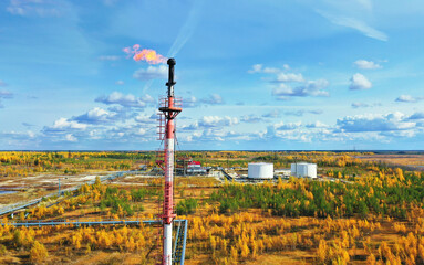 Autumn industrial landscape. Western Siberia. Oil torch. Associated gas burning during oil production.