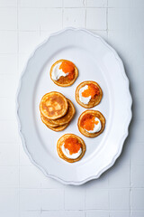 Festive appetizer. Mini Blini pancakes with sour cream and red caviar. Gourmet party food
