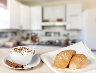 Tasty fresh croissant and cup of coffee on table