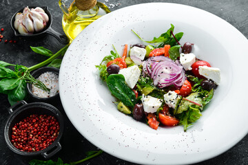 Traditional Greek salad with vegetables. On a black stone background.