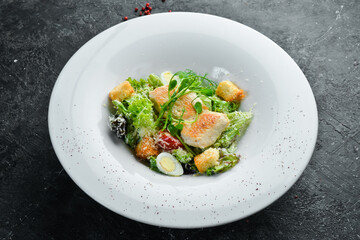 Traditional Caesar salad with chicken. On a black stone background.