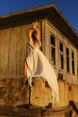 Beautiful blonde girl dances on the seashore near landing stage.