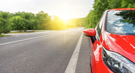 Obraz na płótnie Canvas Red car on the road at sunset.
