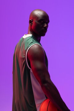 Image of portrait of african american basketball player with basketball on neon purple background