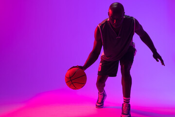 Image of african american basketball player bouncing basketball on neon purple background