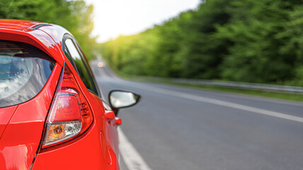 Red car on the road at sunset.