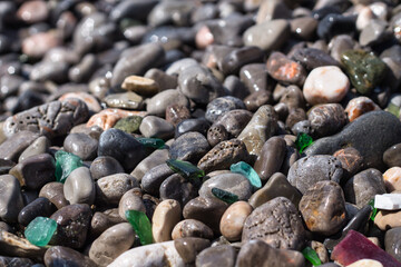 little stones at the beach with various glass shards 