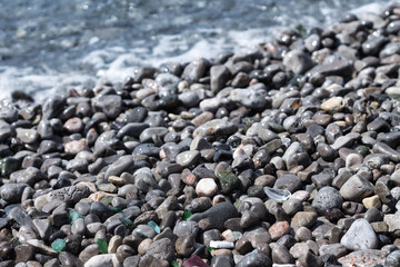 little stones at the beach with various glass shards 