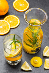 Infused summer drink with oranges, blueberries and rosemary in glass and bottle.