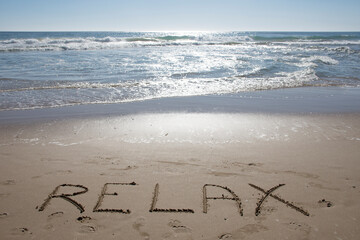 Empty Ocean View from the beach shore with relax word on the sand