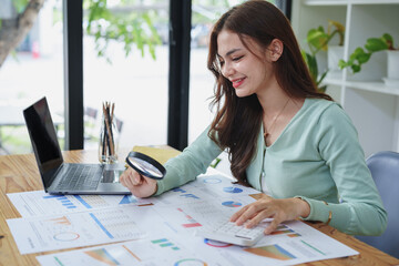 accountant holding a magnifying glass and using a calculator to check financial statements