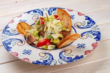 Salad with roast pork and capers. On a light background.