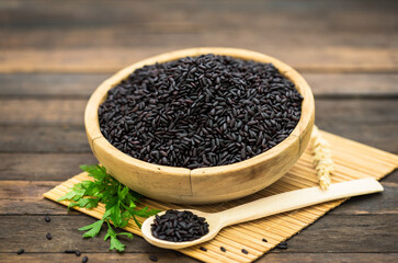 Uncooked black rice on wooden background