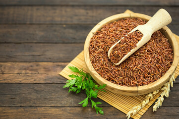 Uncooked red rice on wooden background