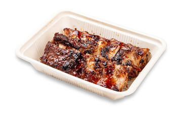 Grilled pork ribs. In a plastic container. Food to go. On a light background.