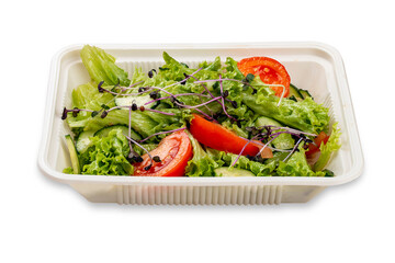 Salad with fresh vegetables and microgreens. In a plastic container. Food to go. On a light background.