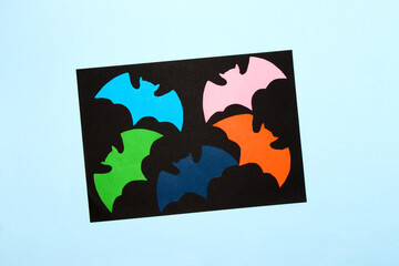 colorful bats on the black part of the background, around the black is the blue background, creative art halloween design, craft paper, flat lay
