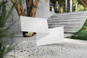 Clean minimal business card mockup floating on marble bench with plant
