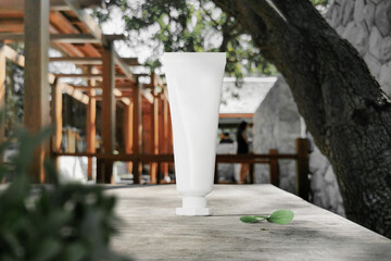 Clean minimal cream tube packaging mockup standing on bench with plant and leaves