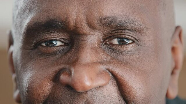 Extreme close-up macro shooting male wrinkled African face looking at camera with dark eyes smile unrecognizable man has good eyesight happy after successful laser vision correction ophthalmology