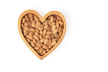 Almond in a heart shaped wooden plate isolated on white background. Products for heart health. Copy...