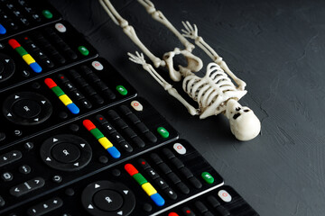 the skeleton of a person lies diagonally down, parallel to it are remote controls from the TV