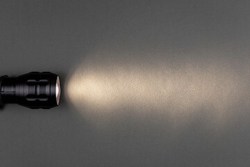 A bright beam of light from a flashlight shines on a gray background