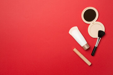 Makeup products for skin tone on color background, top view