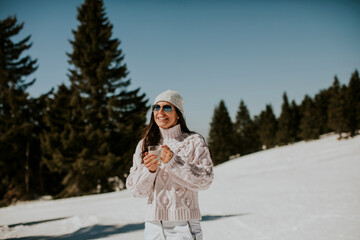 Fototapeta na wymiar Young woman drinking lemonade on the mountain ski track
