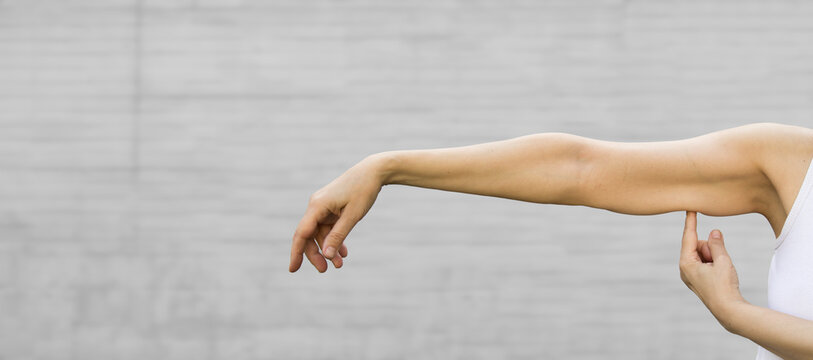 A Woman Shows The Flabby Muscles Of The Arm . Flabby Arm Syndrome (FAS). Effect Of Aging Caused By Loss Of Elasticity And Muscle.Banner, Copyspace.