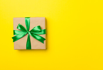 Gift box with red ribbon bow on color background, top view