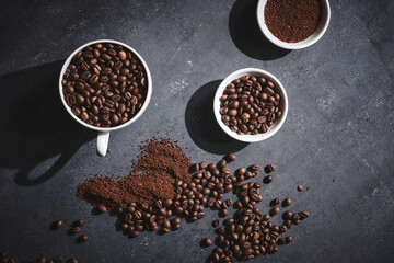 White cup of freshly brewed roasted coffee beans on gray background