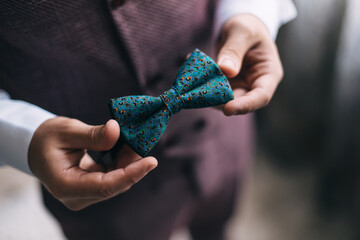 close-up of a man's hand holding a green bow tie