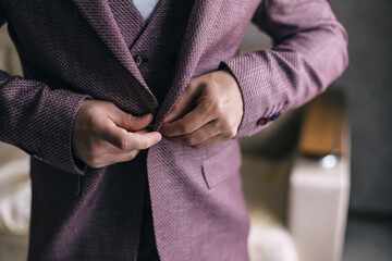 the groom fastens a button on his jacket, Morning of the groom before the ceremony.